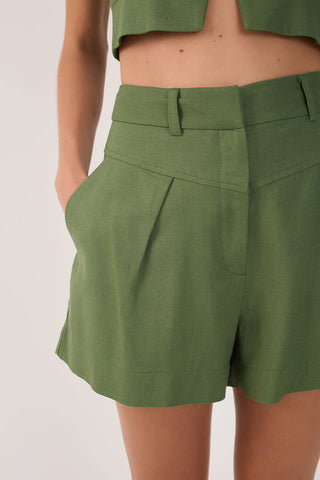 Close-up of woman wearing green pleated shorts. 
