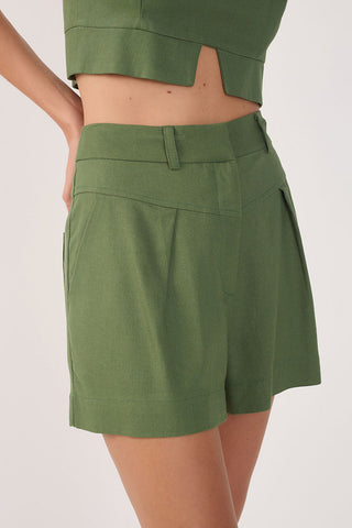 Close-up of woman wearing green pleated shorts. 