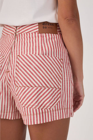 Back of woman wearing red and white stripe shorts with "dress to denim" label. 