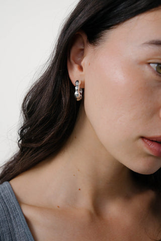 Close-up of model wearing sterling silver hoop earrings. 