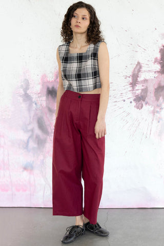 Woman wearing black and white plaid square neck tank top with wide leg burgundy pants. 