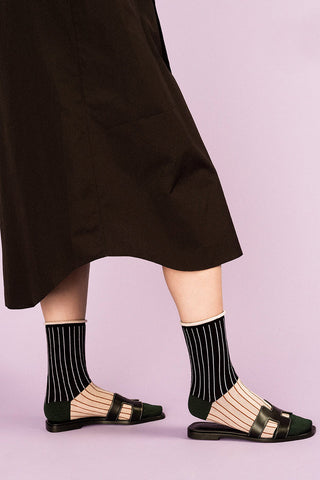 Close-up of women's leg wearing black and cream striped Homeroom crew socks by Hansel from Basel. 