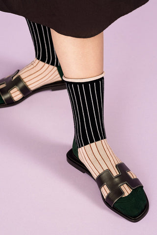 Close-up of women's leg wearing black and cream striped Homeroom crew socks by Hansel from Basel. 