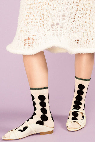 Close-up of women's leg wearing ivory and black dot Marble Crew Socks by Hansel from Basel. 