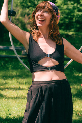Woman in garden wearing black cropped tank with cut-out detail. 