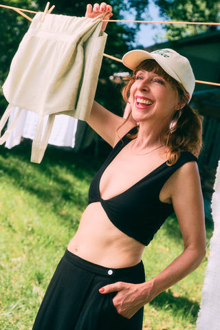 Woman at close-line wearing deep V-neck cropped tank and beige baseball cap. 