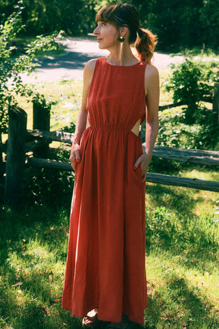 Woman in garden wearing red maxi dress with side cut-outs.  
