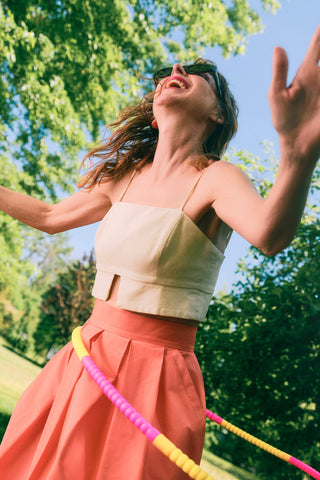 Jennifer Glasgow wearing beige cropped top with coral pleated skirt. 