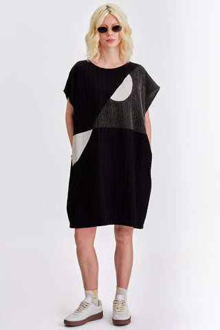 Woman in front of  white background wearing black and white colour blocked relaxed fit tunic. 