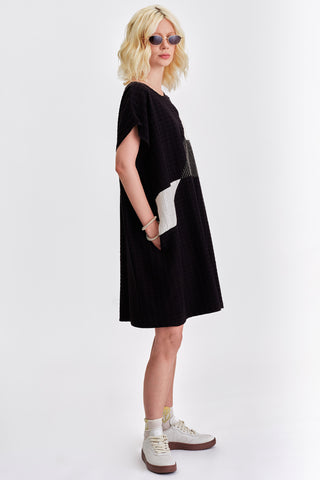 Woman in front of  white background wearing black and white colour blocked relaxed fit tunic. 