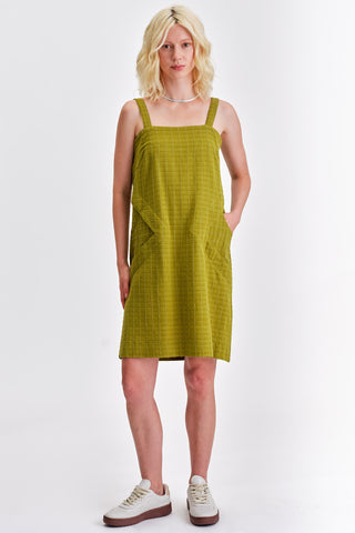 Woman in front of white background wearing green knee length summer dress. 
