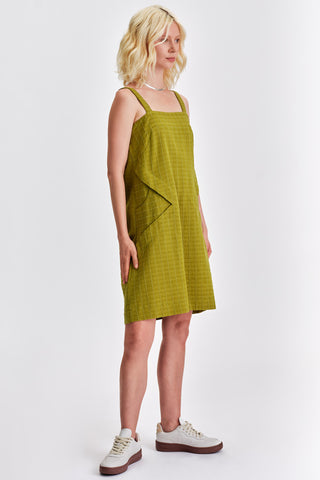 Woman in front of white background wearing green knee length summer dress. 
