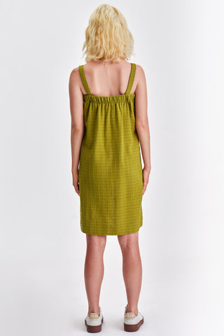 Back view of woman in front of white background wearing green knee length summer dress. 