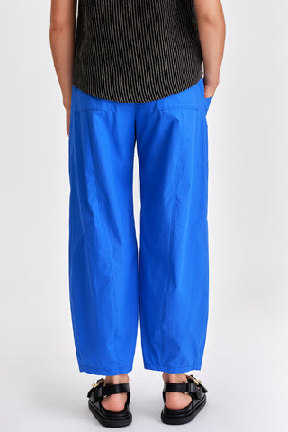 Back view of woman wearing black stripe tanktop, blue pants and black sandals. 