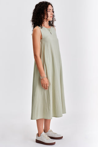 Woman wearing light green sleeveless belted midi dress with white sneakers. 