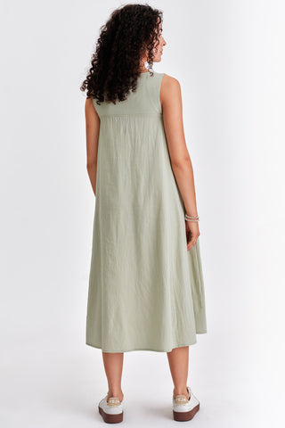 Back view of woman wearing light green sleeveless belted midi dress with white sneakers. 
