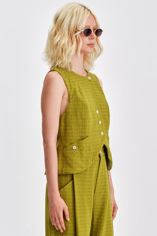 Woman wearing olive green button up vest with matching pants. 
