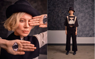 Left side of image features model with blond hair and black hat holds hands up in front of her face, with eyes painted on her palm. Right side of image features the same model, wearing a rose beige, tan and black colour blocked cropped shirt with ankle length black pants. She stands in front of a grey studio background. 