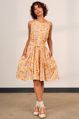 Woman wearing pink and yellow floral printed Astra belted sundress by Jennifer Glasgow. 