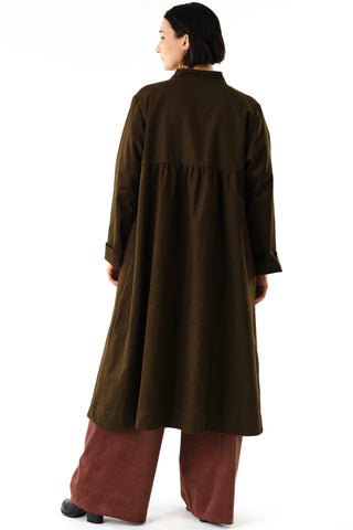 Back view of woman in front of white background wearing olive oversized Aterian swing coat by Jennifer Glasgow. 