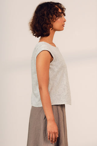 Side view of woman wearing white check pleated Aurora top by Jennifer Glasgow. 