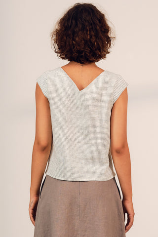 Back view of woman wearing white check pleated Aurora top by Jennifer Glasgow. 