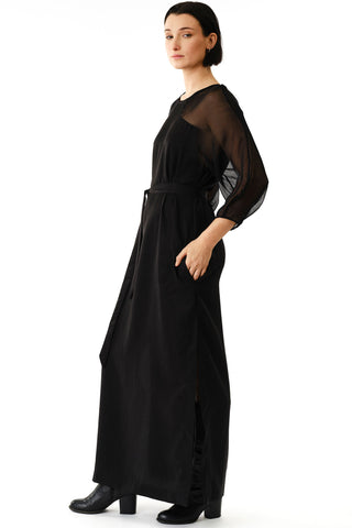 Side view of woman in front of white background wearing black full length Betana Dress by Jennifer Glasgow. 