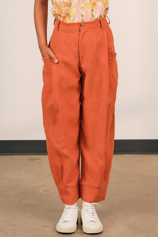Closeup of woman wearing pumpkin orange linen Ceres pants by Jennifer Glasgow. 