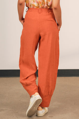 Back view of woman wearing pumpkin orange linen Ceres pants by Jennifer Glasgow. 