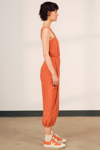 Model wearing pumpkin orange OEKO-TEK linen Danu jumpsuit by Jennifer Glasgow. 