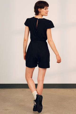 Back view of model wearing a black crinkle cotton short Eula romper by Jennnifer Glasgow. 