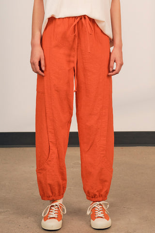 Woman wearing coral red cotton track inspired Finnely Pants by Jennifer Glasgow. 