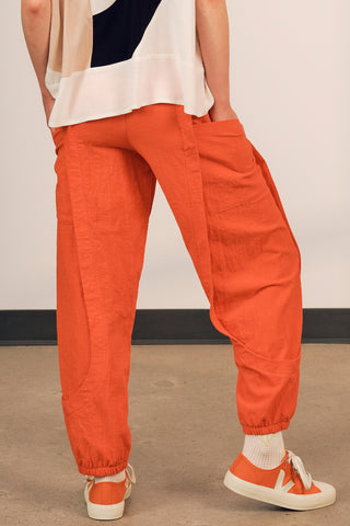 Back view of woman wearing coral red cotton track inspired Finnely Pants by Jennifer Glasgow. 