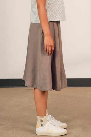 Side view of woman wearing grey linen aline pleated Galleon skirt by Jennifer Glasgow. 
