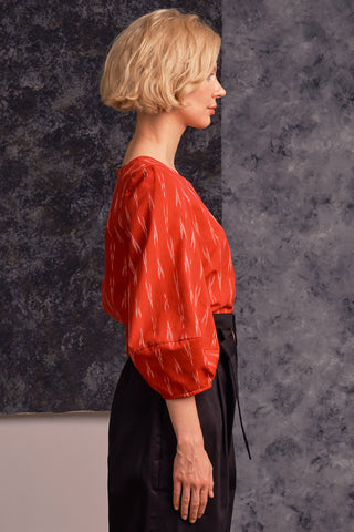 Side view of model wearing red Ikat Hania Blouse by Jennifer Glasgow. 