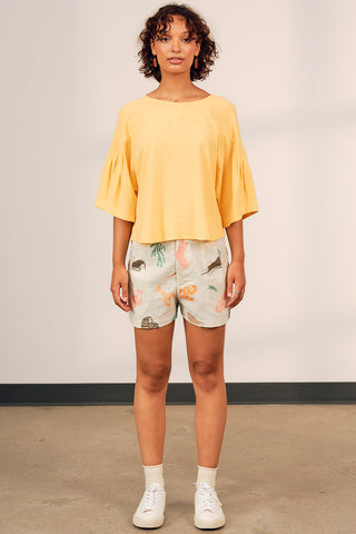 Woman wearing yellow top with printed Lilith shorts by Jennifer Glasgow. 