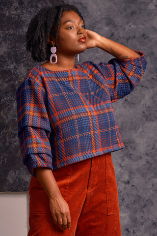 Model wearing plaid Maraja shirt by Jennifer Glasgow with boat neck and pleated sleeves. 