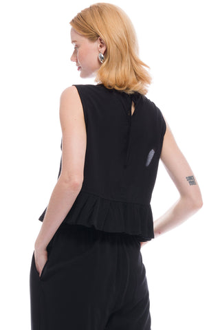 Back view of woman wearing black rayon Matille ruffle top by Toit Volante. 