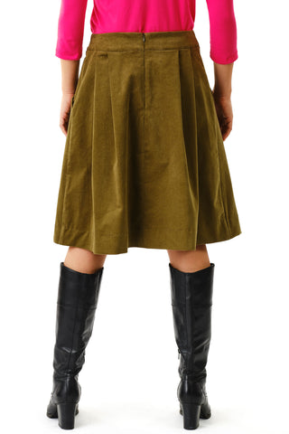 Back view close-up of woman against white background wearing olive green corduroy knee length Musica skirt by Jennifer Glasgow and black boots. 