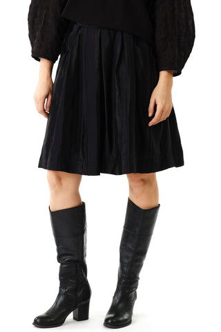 Woman in front of white background wearing black knee length Strenua skirt by Jennifer Glasgow and black boots.  