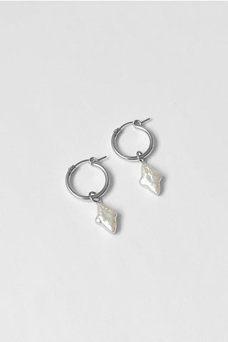 Sterling silver hoop earrings with freshwater pearl pendant charms, shown on white background. 