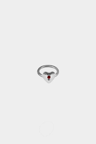 A silver heart-shaped ring with a small ruby gemstone in the center, displayed on a light gray background.