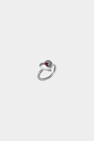 A silver heart-shaped ring with a small ruby gemstone in the center, displayed on a light gray background.