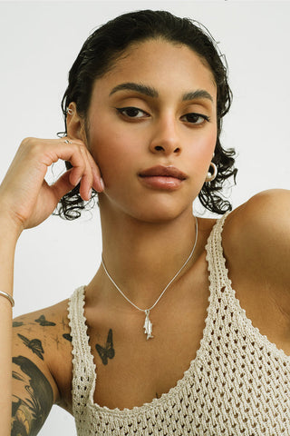 A close-up of model wearing silver chain with Lucky Fish pendant. 