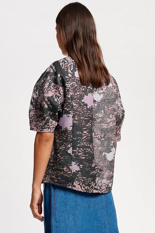 Back view of woman, in front of white background, wearing black and purple printed Kloke jacquard Forge shirt. 