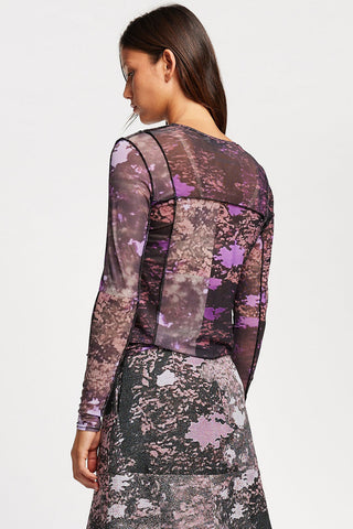 Back view of woman, in front of a plain white background, wearing semi-sheer long sleeve purple tree print Inlet shirt by Kloke. 