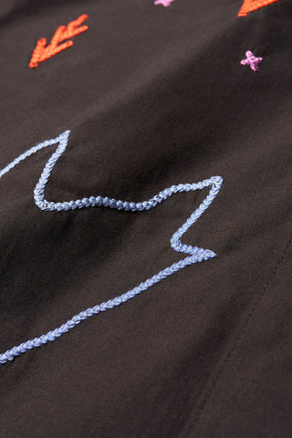 Closeup of colourful embroidery on black cotton of Kloke Universe skirt. 