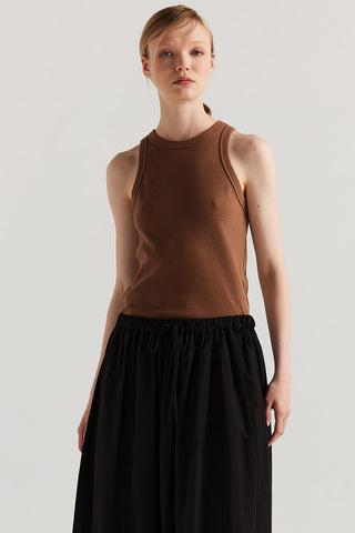 Woman wearing brown racer back tank top and black drawstring waist skirt. 