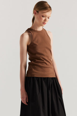 Woman wearing brown racer back tank top and black drawstring waist skirt. 