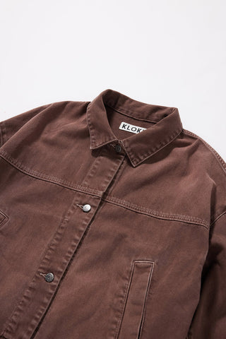 Brown denim jacket with a visible Kloke brand label on inside neck on a white background